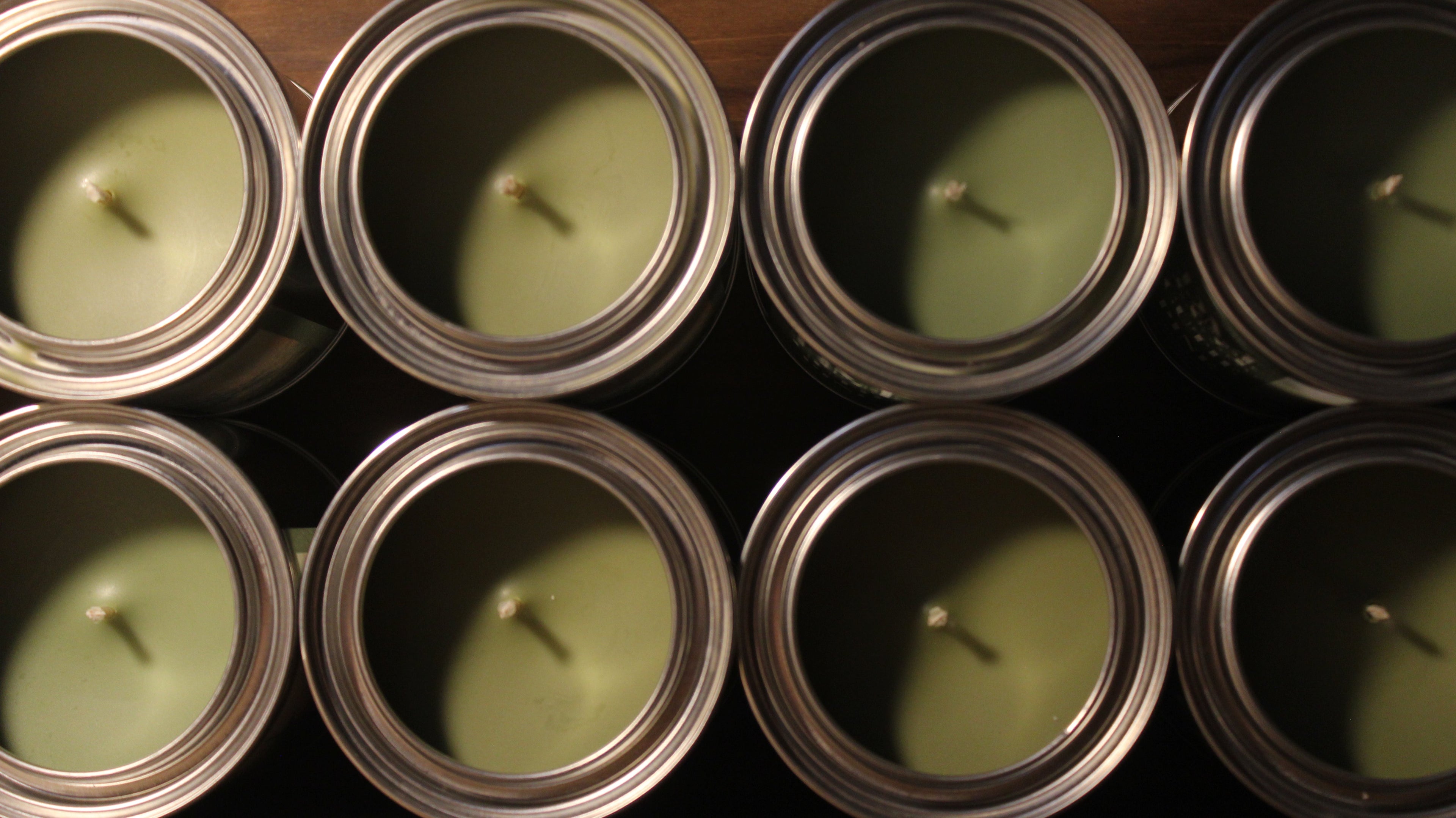 green colored candles in rustic metal tins