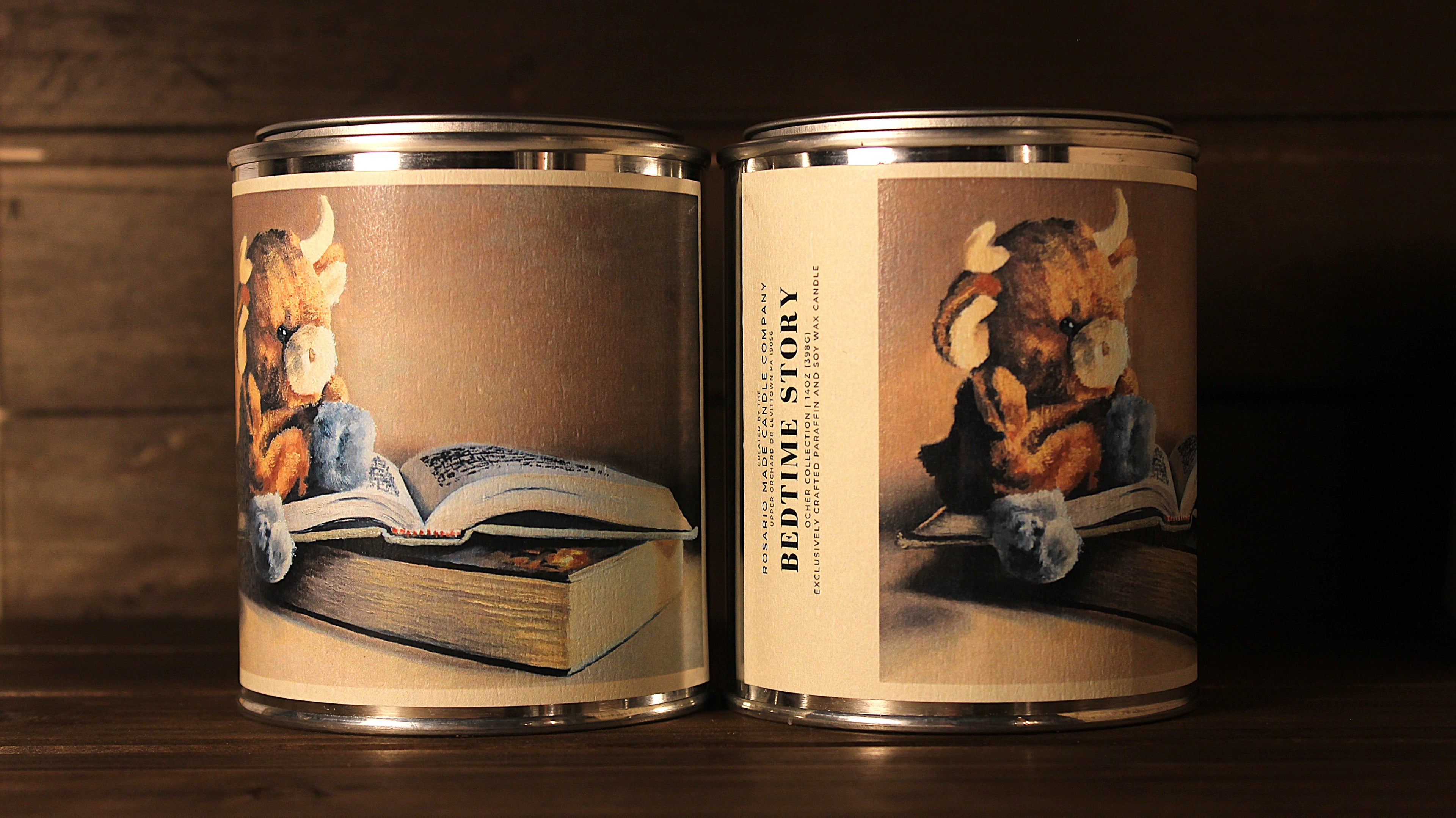 Two tin soy wax candles with illustrated labels featuring children's bedtime stories on a wooden surface.