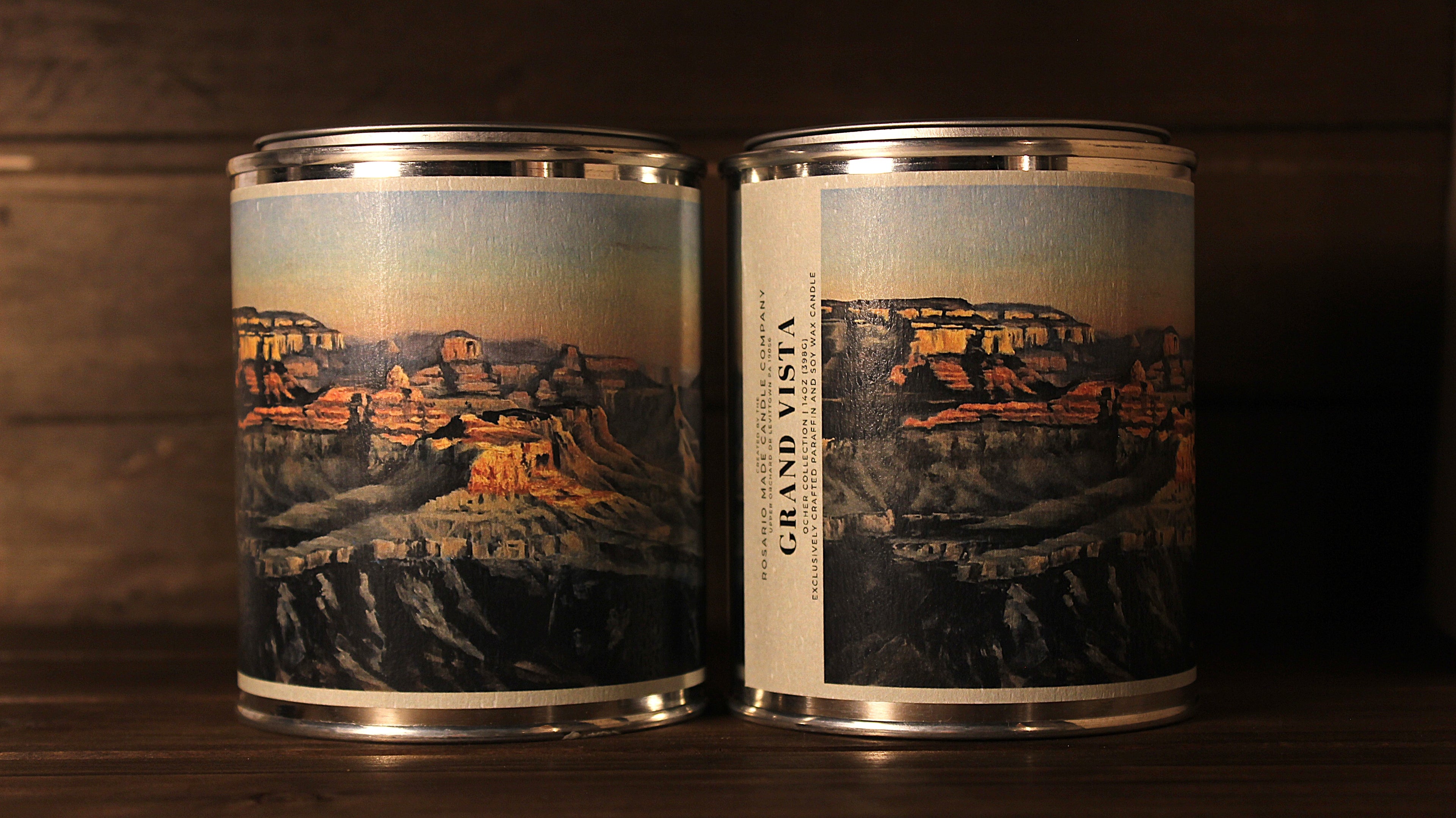Two tin soy wax candles with Grand Canyon-themed labels on a wooden surface.